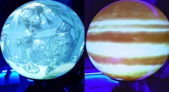 The Magic Planet digital globe glowing in the dark planetarium, shown twice with two different planets projected on it