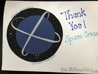 The front of a handmade card with a drawn planet, reading Thank You! Space Crew, from Ms. McDonald's Class